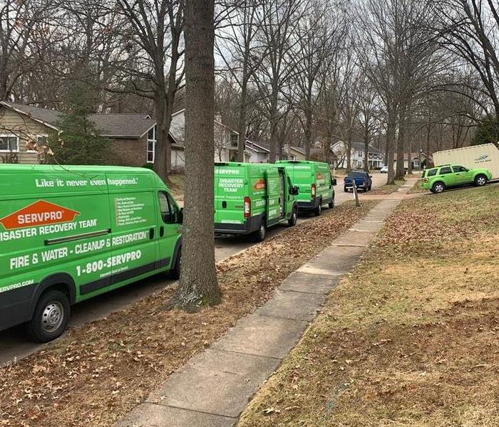 Three SERVPRO vans and one SUV parked outside a home. 