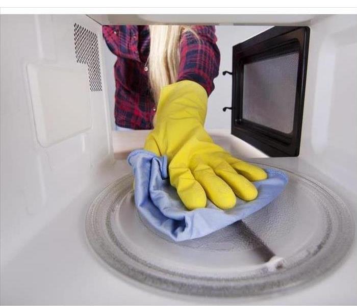 woman cleaning the inside of a microwave