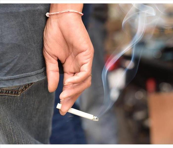 Image of cigarette in man's hand with smoke.